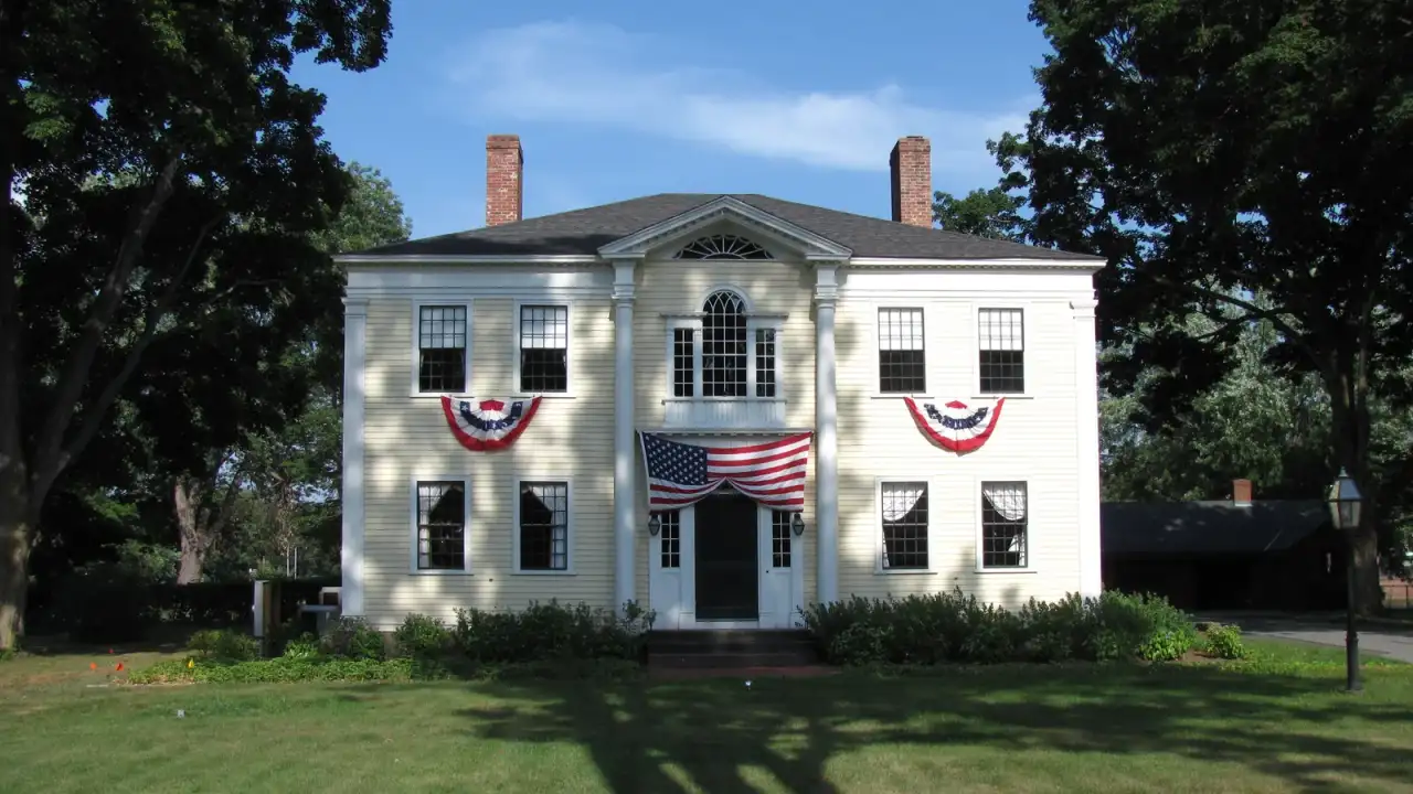 Federal-era Captain Charles Leonard House with white clapboards and flag bunting on the village green, Agawam, Massachusetts