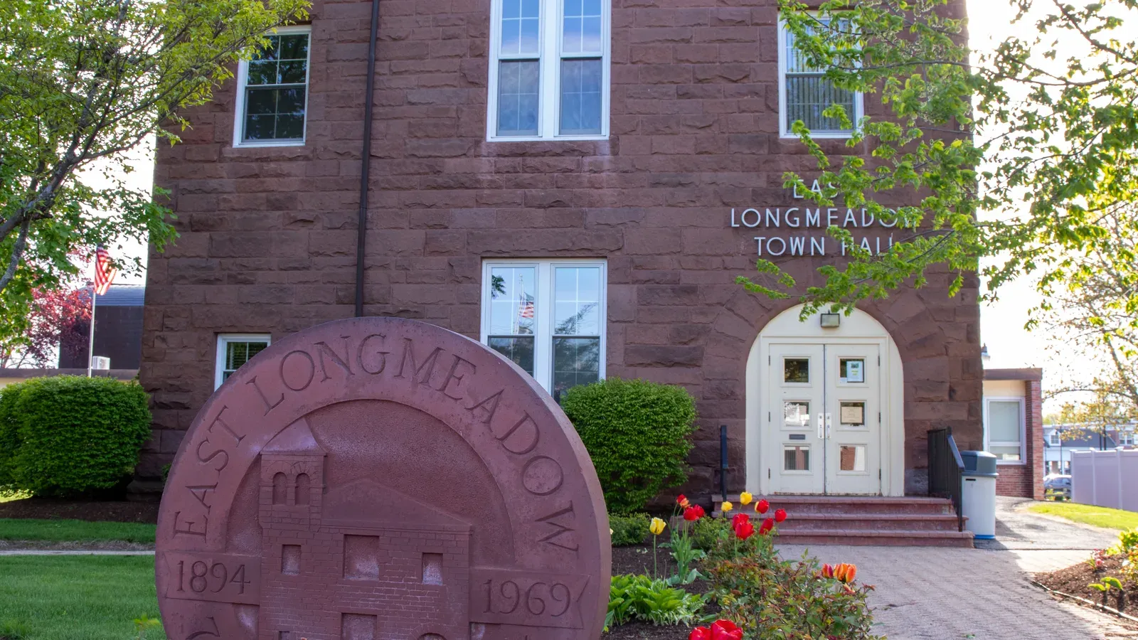 Brownstone town hall with the carved town seal and spring tulips, East Longmeadow, Massachusetts