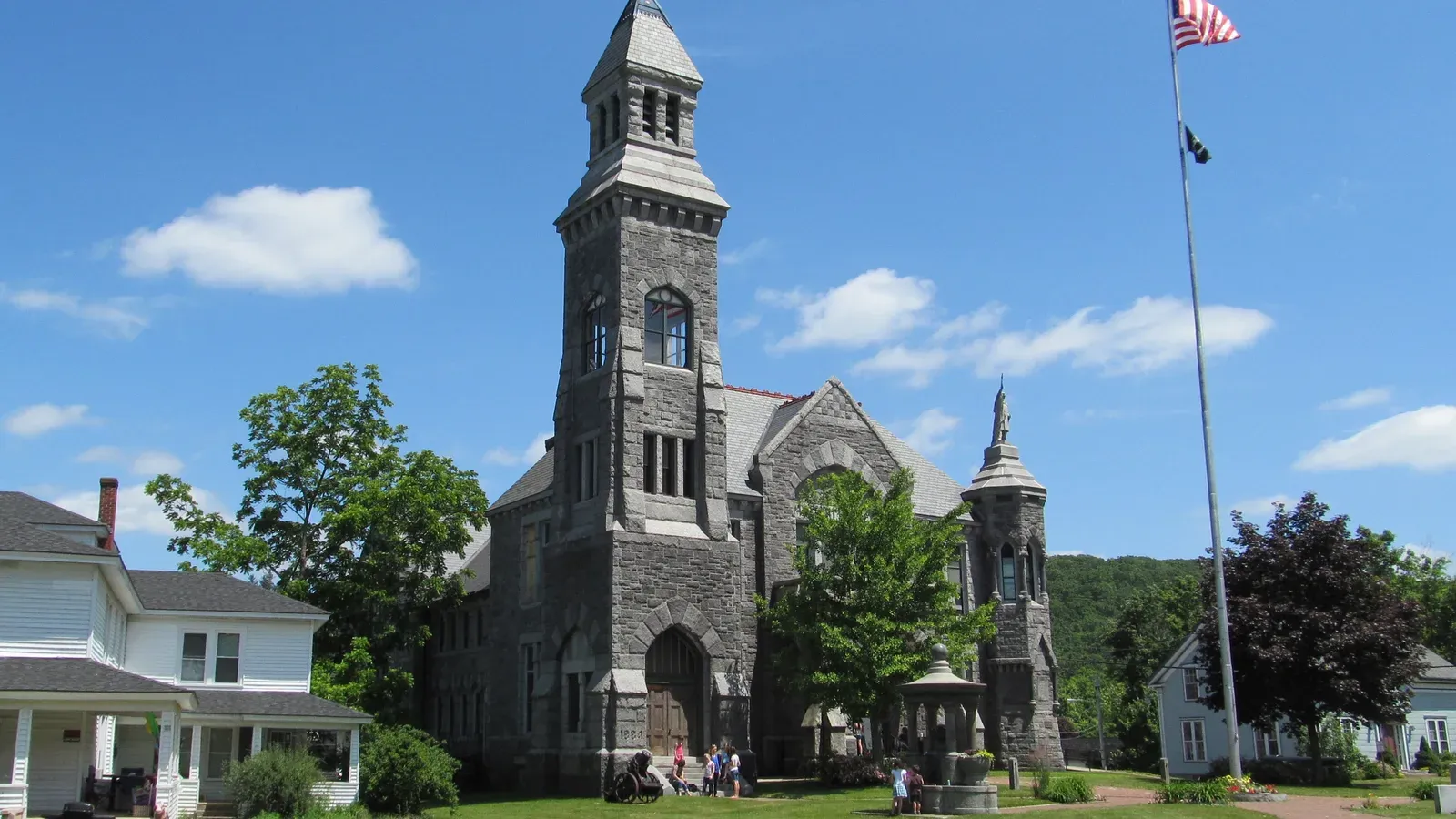 Granite Richardsonian Romanesque Memorial Hall with a corner tower and American flag, Monson, Massachusetts
